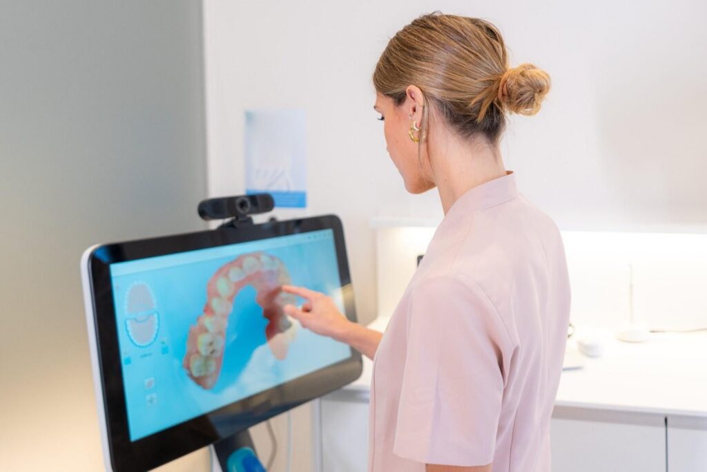 Dentist reviewing 3D dental scan on digital screen in clinic