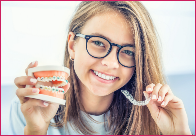 Child holding an orthodontic model and clear aligner.
