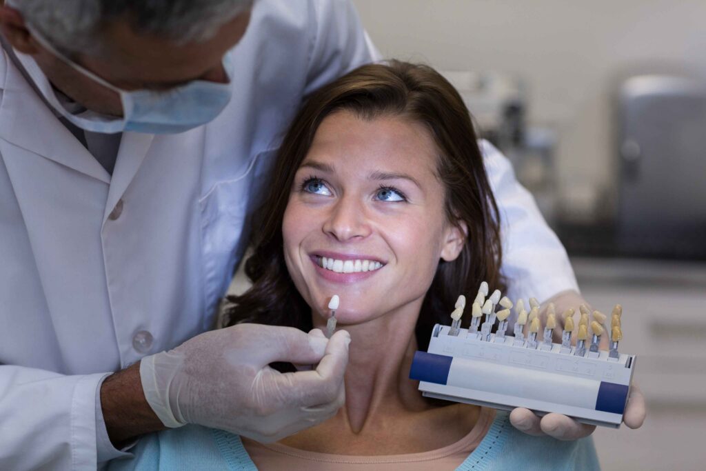 Dentist matching tooth shade with smiling patient