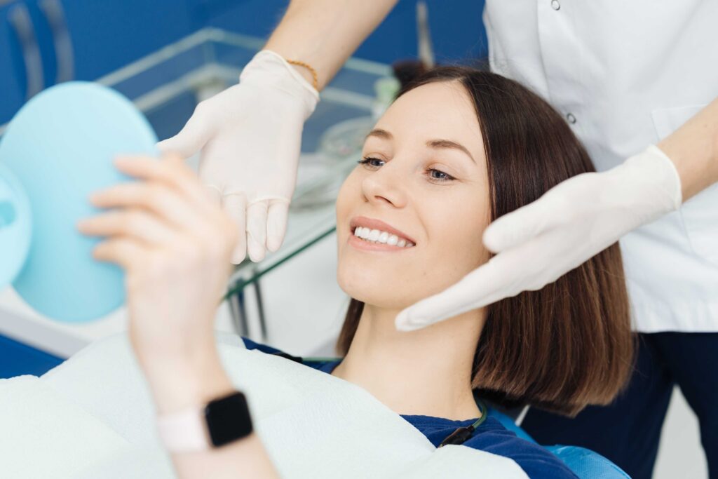 Patient checking smile with handheld mirror after treatment