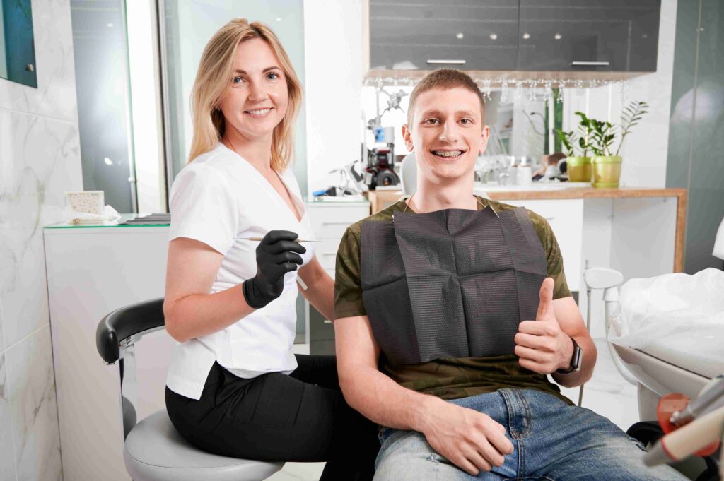 Smiling patient giving thumbs up with dental professional.