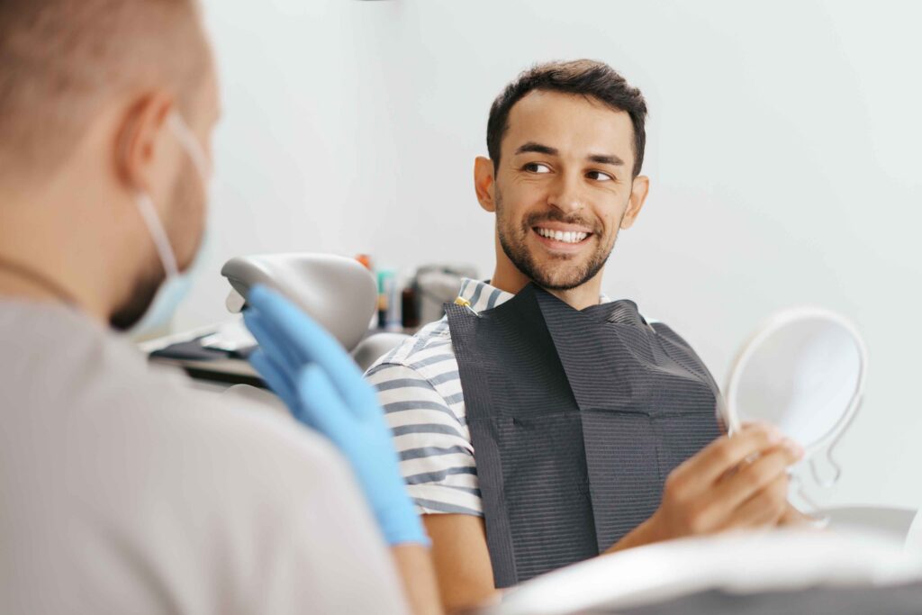 Smiling patient holding a dental mirror.
