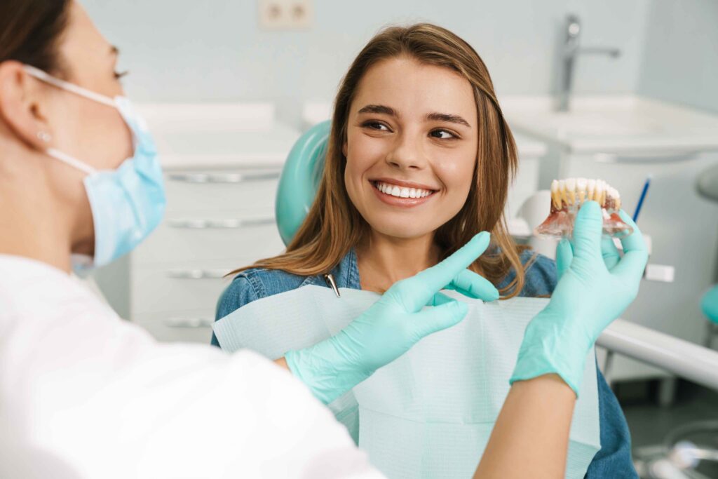 Dentist showing a dental model to a smiling patient.